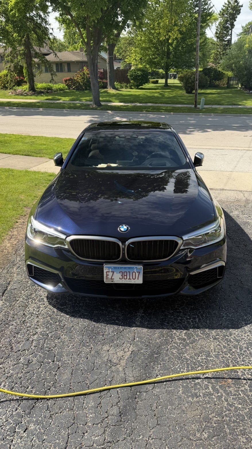 Slipstream-detailed black BMW sedan with showroom finish on a suburban driveway