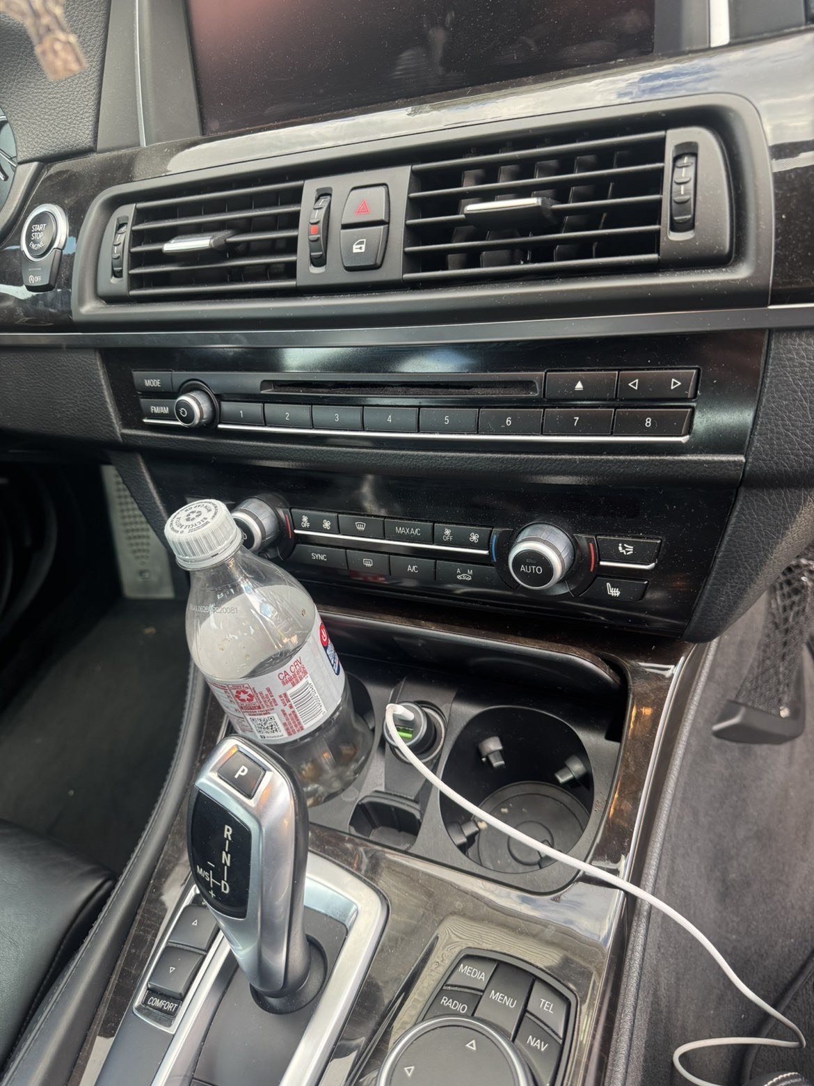 Before: car dashboard covered in dust with water bottle and phone charging cable cluttering the cup holder